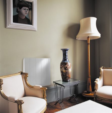 Gilt-framed French armchairs and tall vase on glass-topped metal table in living room with cream standard lamp